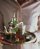 Hands holding tray of mint tea