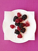 Fresh raspberries and blackberries on plate with napkin