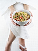 Person in bathrobe holding small bowl of quinoa salad