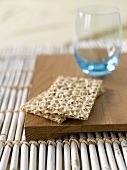Wholemeal crispbread and tumbler on wooden board