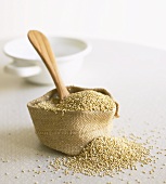 Quinoa in small sack with wooden spoon