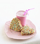 Heart-shaped jam biscuits with sprinkles and shake