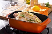 Whole chicken with rosemary and lemon in a roasting dish