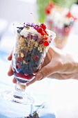 Hand holding a glass of berry muesli