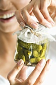 Hands holding a jar of pickled gherkins