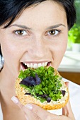 Young woman eating a slice of bread topped with herbs