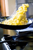 Food being tossed in a frying pan