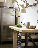 Blick in Küche mit Edelstahl-Kühlschrank, Küchentisch mit Spüle & klassischen Klemmlampen