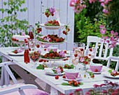 Outdoor table laid for coffee with strawberries & mallow flowers