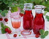 Strawberry syrup in bottles & in a glass diluted with water