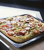 Sausage and vegetable pizza on a baking tray