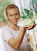 A young woman holding a kohlrabi