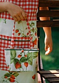 A girl wearing and apron and carring a bag with a strawberry pattern