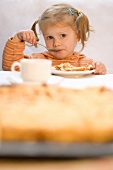 A little girl eating quince cake