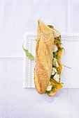 A chicken and mango sandwich on baguette bread