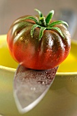 A beefsteak tomato on a sharp knife