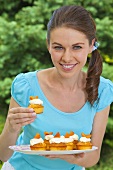 Junge Frau hält Tablett mit Aprikosenmuffins