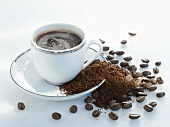 A cup of coffee, coffee powder and coffee beans