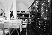 A black and white photo of a designer restaurant with a vaulted ceiling and wine racks