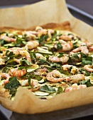 Pizza topped with prawns, vegetables & herbs on baking tray