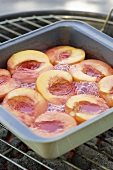 Cooking peaches in a baking dish on the barbecue