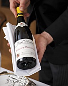 Kellner bietet eine Flasche Weißwein an