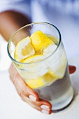 Hand hält ein Glas Zitronenlimonade
