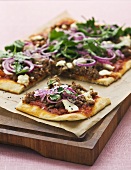 Pizza topped with mince, cheese, onions and sesame seeds