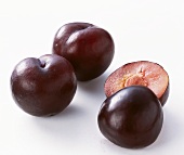 Two whole and one halved plum (variety: Angeleno)