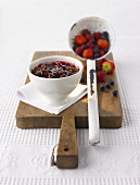 Mixed berry jam in a small bowl, fresh berries in ladle