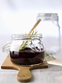 Raspberry & blueberry jam in jar with sprig of rosemary
