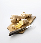 Ginger root, partly sliced, on chopping board