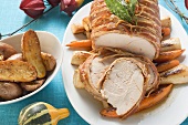 Bacon-wrapped turkey breast (partly carved) on root vegetables