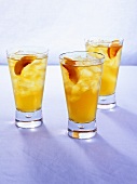 Three peach drinks with ice cubes