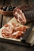 Coppa, partly sliced, on a wooden board