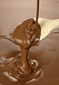 Melted chocolate for chocolate fondue running from wooden spoon