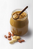 A jar of peanut butter with fresh peanuts