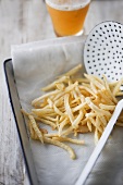 Pommes frites auf Küchenpapier, Glas Bier