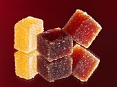 Three cubes of sugar-coated fruit jelly with reflection