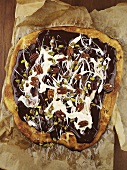 Pizza topped with chocolate sauce, cream and nuts