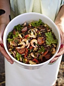 Woman's hands holding bean salad with shrimps