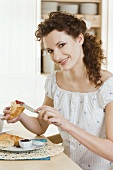 Young woman eating croissant with jam for breakfast