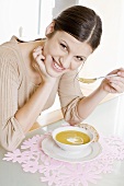 Young woman eating cream of pea soup