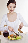 Young woman eating pork steak with boiled potatoes