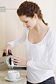 Young woman pouring hot water into a cup