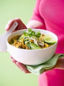 Woman holding a bowl of vegetable curry