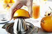 Squeezing an orange with a citrus squeezer