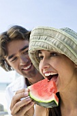 Young couple eating watermelon on beach