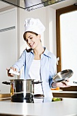 Young woman in chef's hat seasoning soup