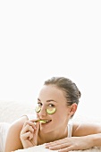 Young woman with cucumber slices under her eyes